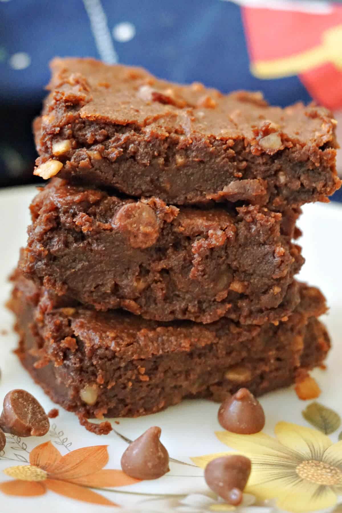 A stack of 3 brownies on a plate.