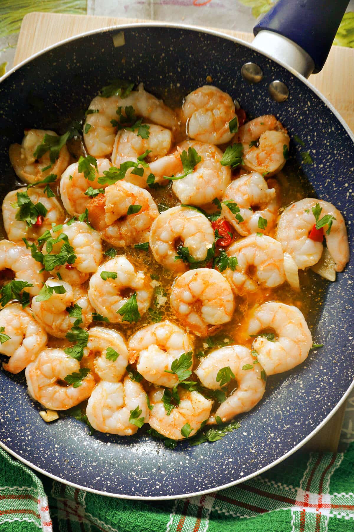 A frying pan with prawns in olive oil sauce.