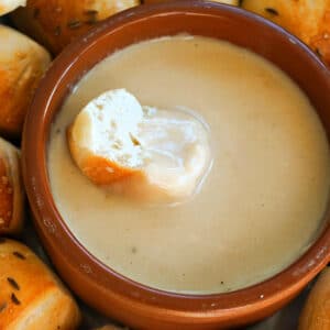 A brown ramekin with Guinness beer cheese dip and a pretzel bite into it.