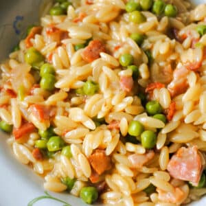 Close-up shoot of a plate with orzo with bacon and peas.
