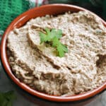 A dish with sardine pate garnished with fresh parsley leaves.