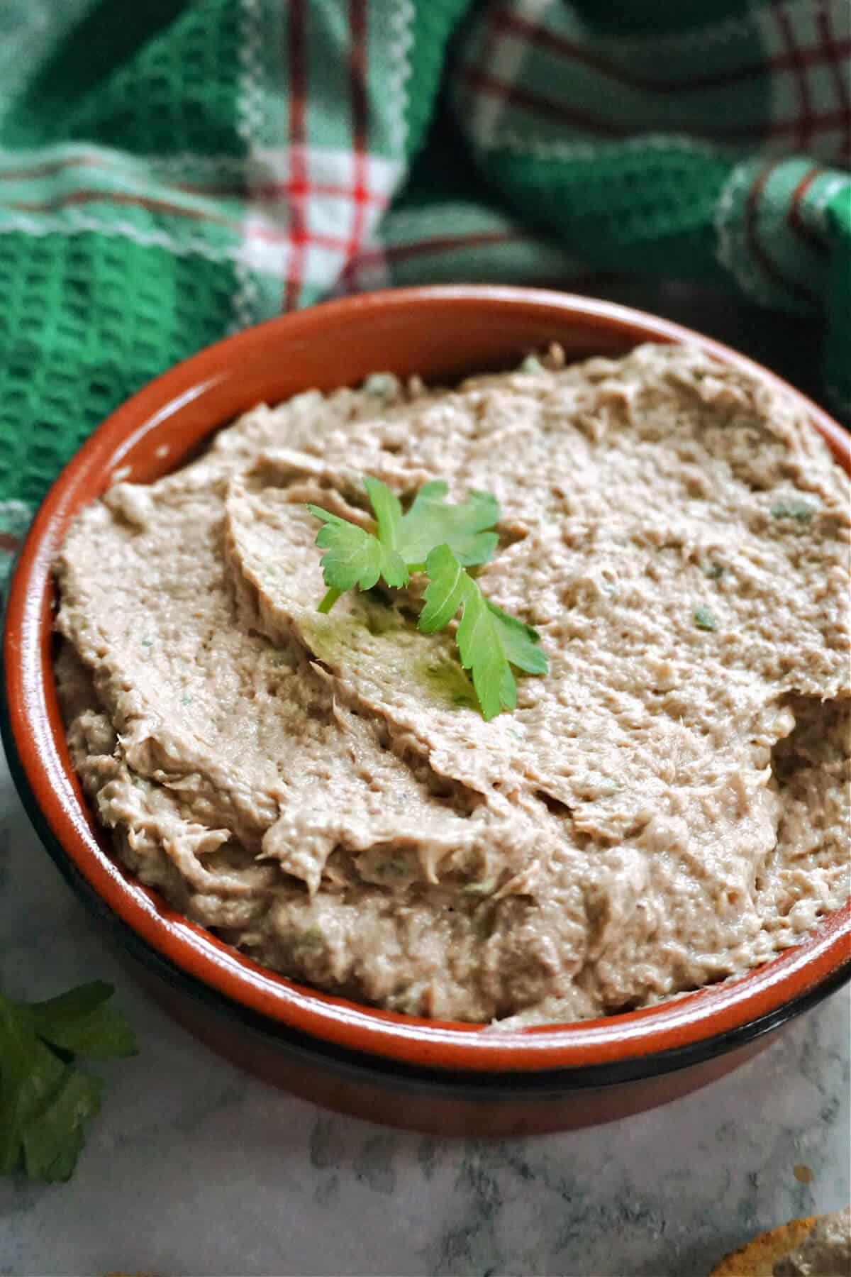 A brown ramekin with sardine pate.