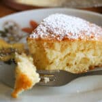 A slice of Irish tea cake on a white plate with a forkful of cake on it.