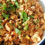 A bowl with pork fried rice garnished with parsley.