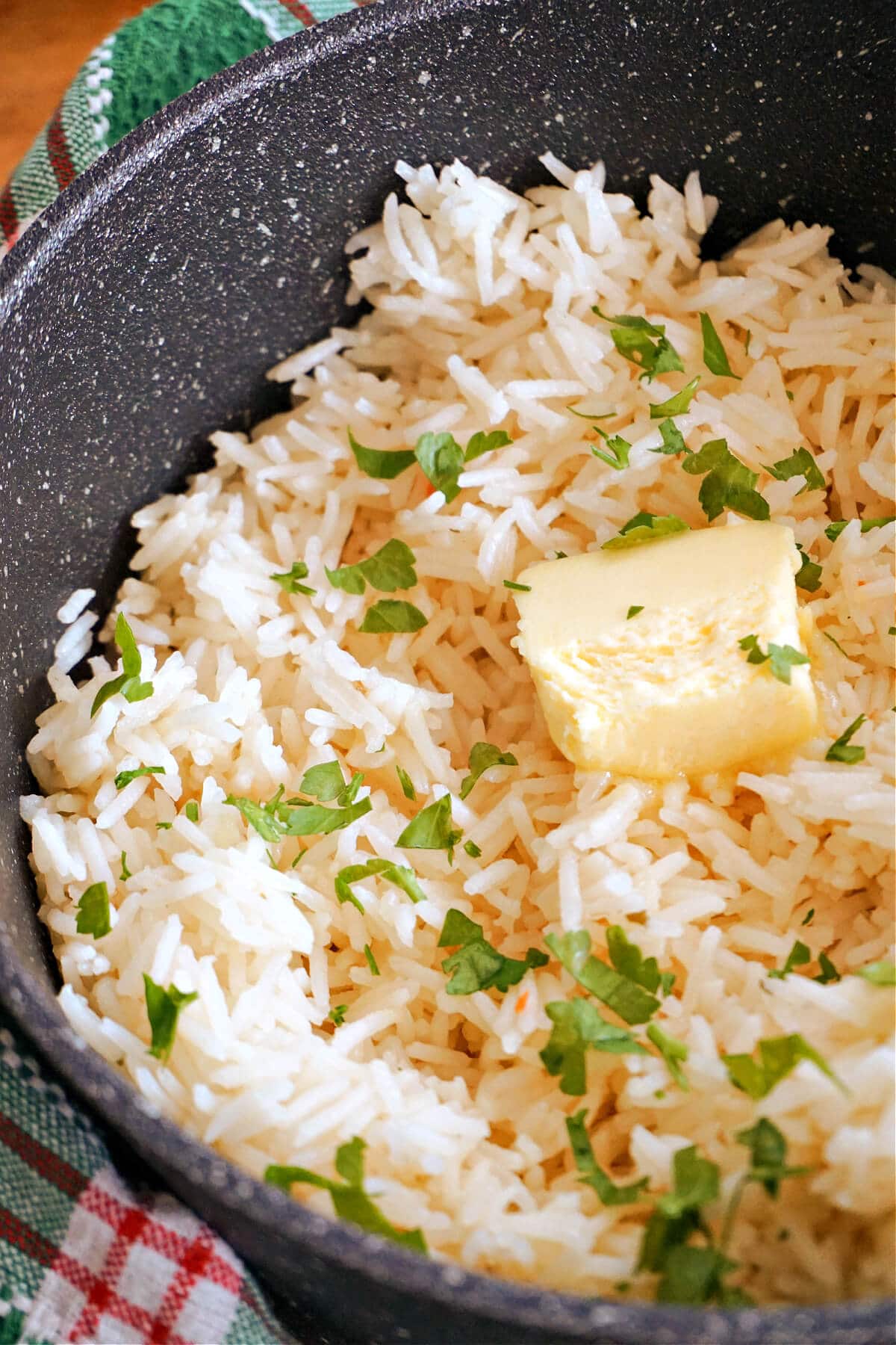 A pot with rice topped with parsley and a knob of butter.