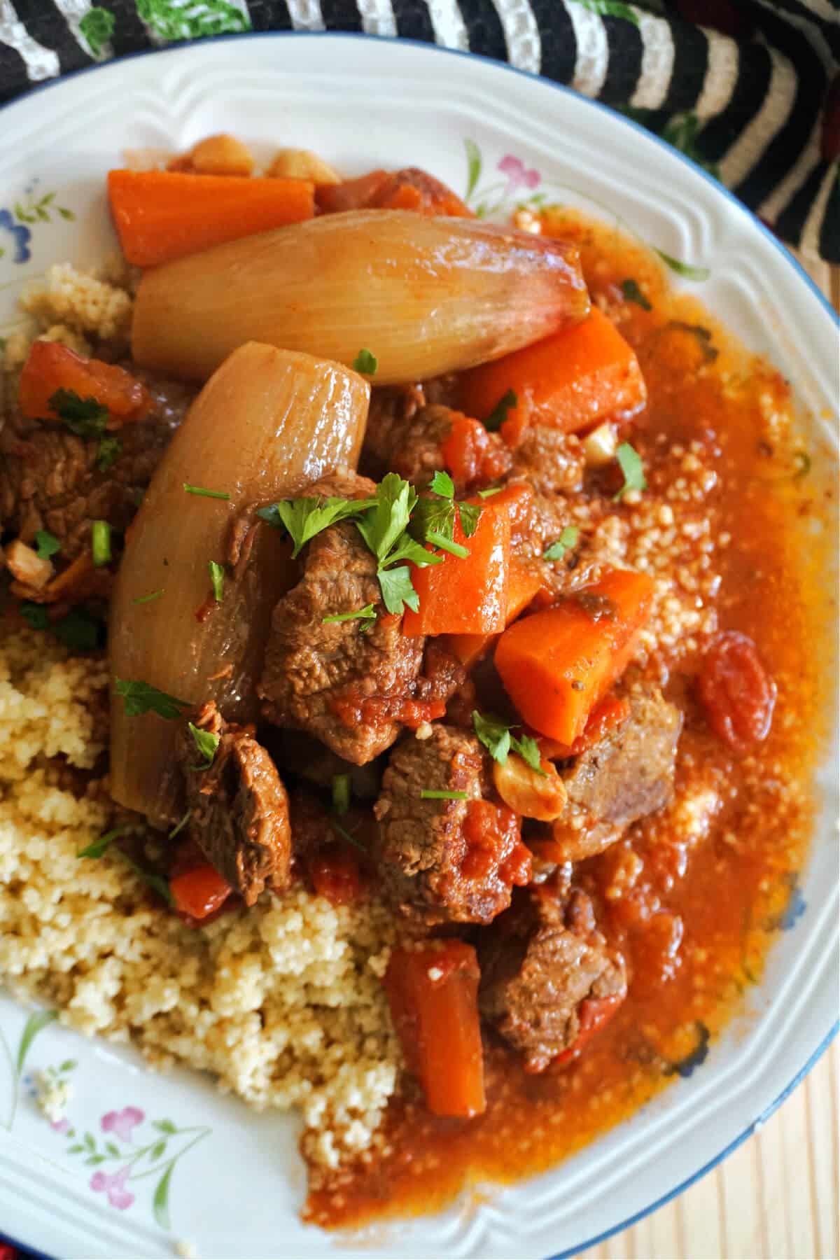 A white plate with couscous and beef stew.