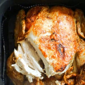 A cooked whole chicken in an air fryer.