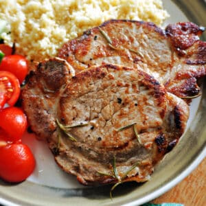 Pork steaks with couscous and cherry tomatoes on a plate.