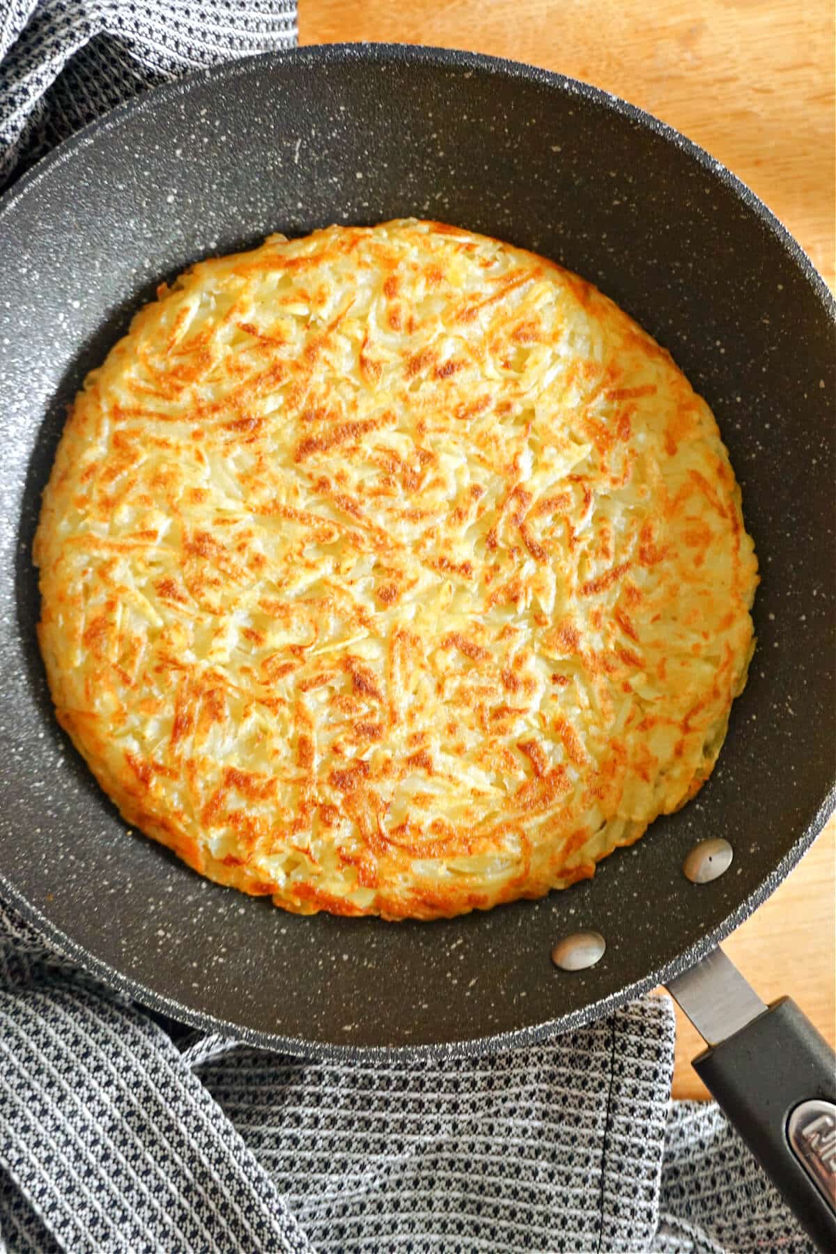 A potato rosti in a frying pan.