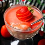 A glass with strawberry mousse topped with a fresh strawberry.