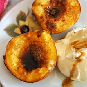 2 air fryer peach halves with a scoop of ice cream on a plate.