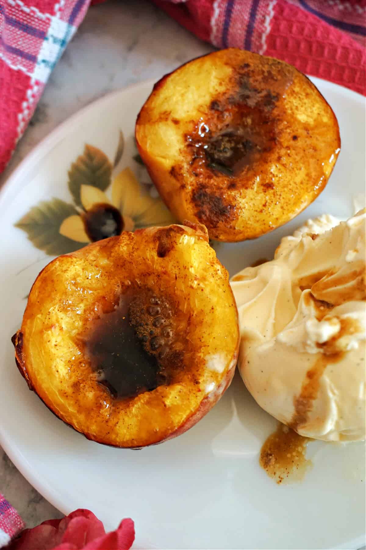 2 halves of a peach drizzled with caramel sauce and a scoop of vanilla ice cream on a plate.