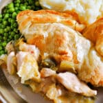 A portion of chicken and leek pie, peas and mashed potatoes on a large plate.
