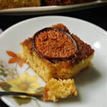 A slice of fig upside down cake with a dessert fork on a flowery plate.