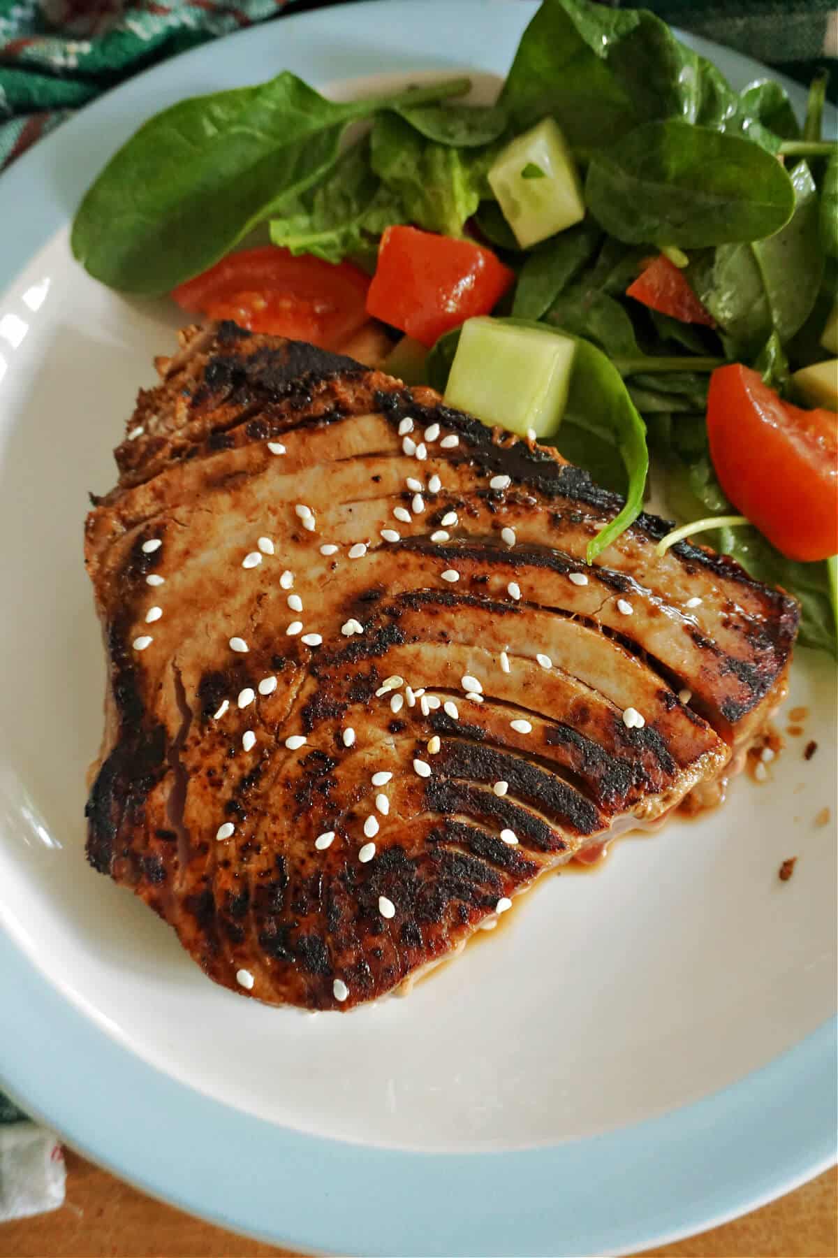 A seared tuna steak with salad on a plate.