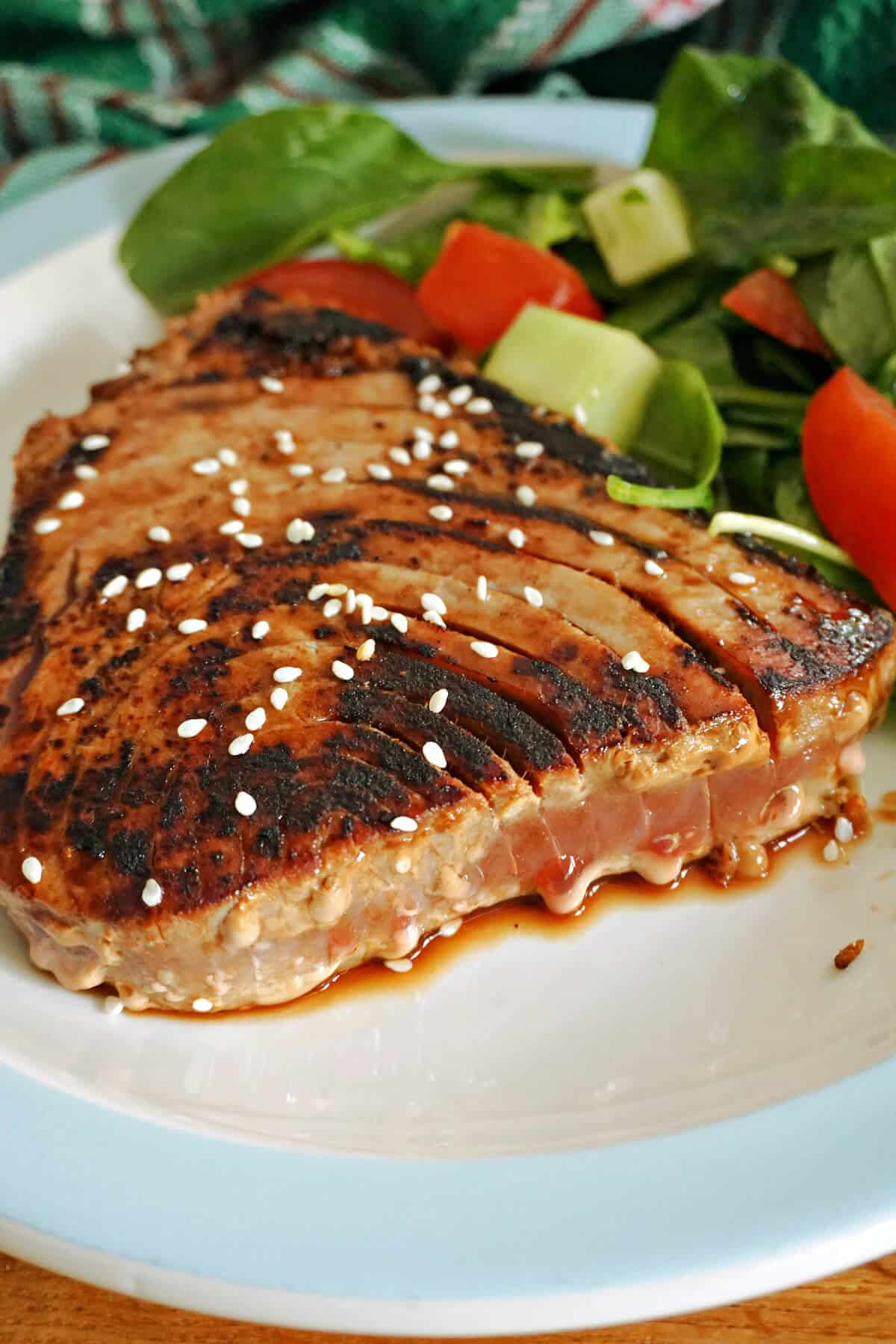 A seared tuna steak with salad on a plate.