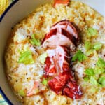 A bowl of saffron risotto with lobster meat and parmesan and garnished with fresh parsley.