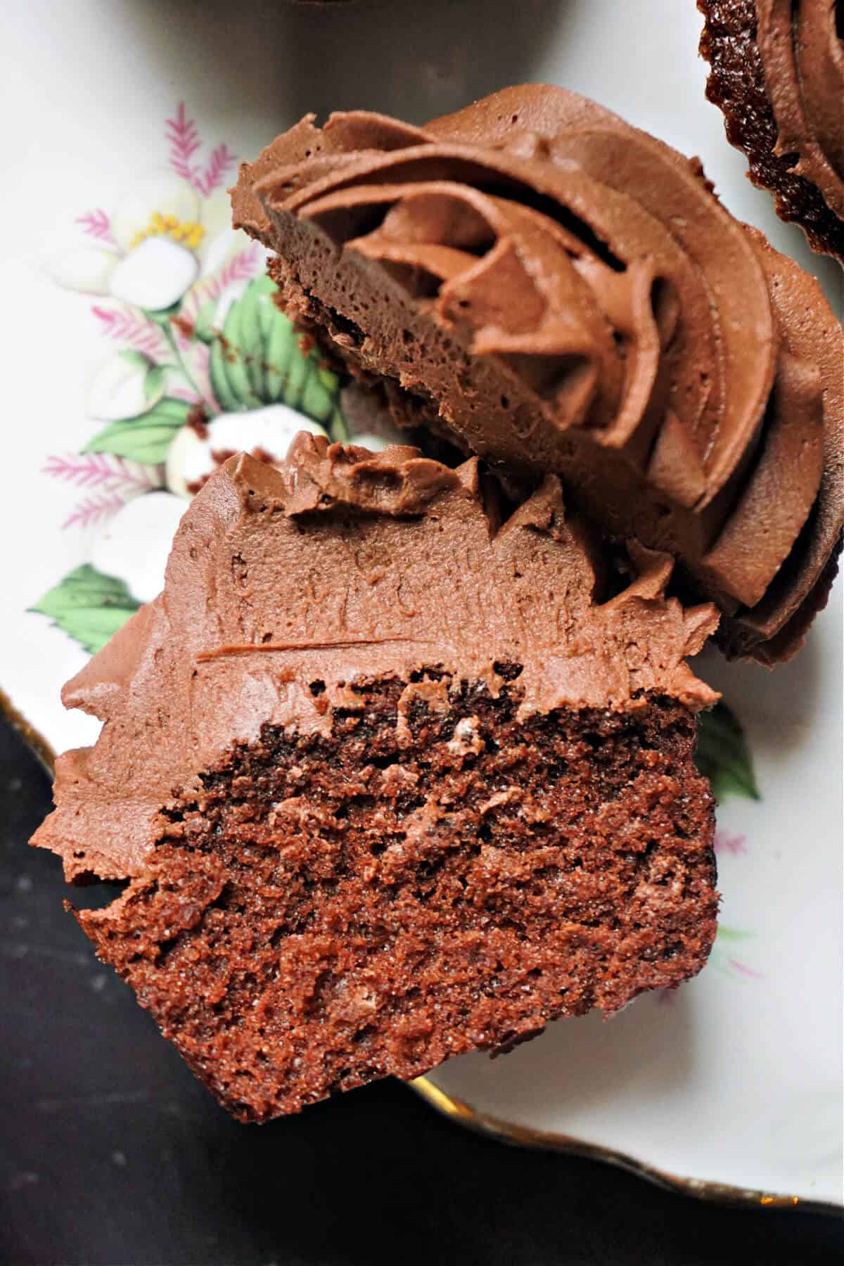A flowery plate with 2 halves of a chocolate cupcake.