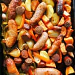 A baking tray with roasted sausages and veggies.