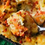 A spoonful of loaded mash over a dish with mash casserole.