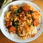 A plate with chicken and chorizo rice garnished with chopped parsley.