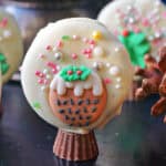 A snow globe cookie with other partially visible cookies in the background.