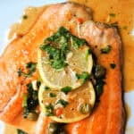 2 trout fillets topped with 2 slices of lemon, and a parsley and caper sauce drizzled over.
