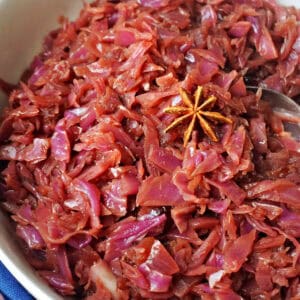 A white bowl with braised red cabbage topped with a star anise.