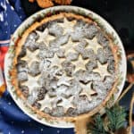 A mince pie topped with stars and dusted with icing sugar.