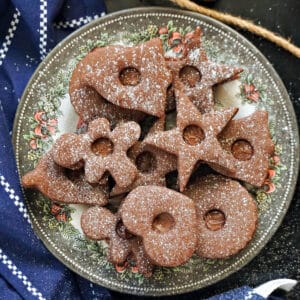 A festive plate with chocolate linzer cookies stuffed with nutella and dusted with icing sugar.
