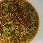 A white ramekin with herby olive oil dip.