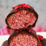 A stack of 2 halves of a raspberry bounty bar on top of other whole bars.