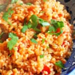 A blue plate with bulgur garnished with chopped parsley.