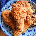 A deep blue plate with fried chicken pieces and a blue tea towel around the plate.