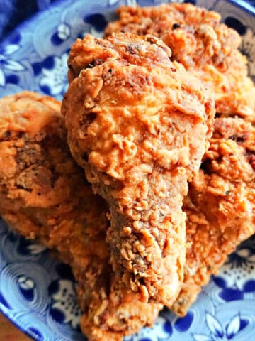 A deep blue plate with fried chicken pieces and a blue tea towel around the plate.