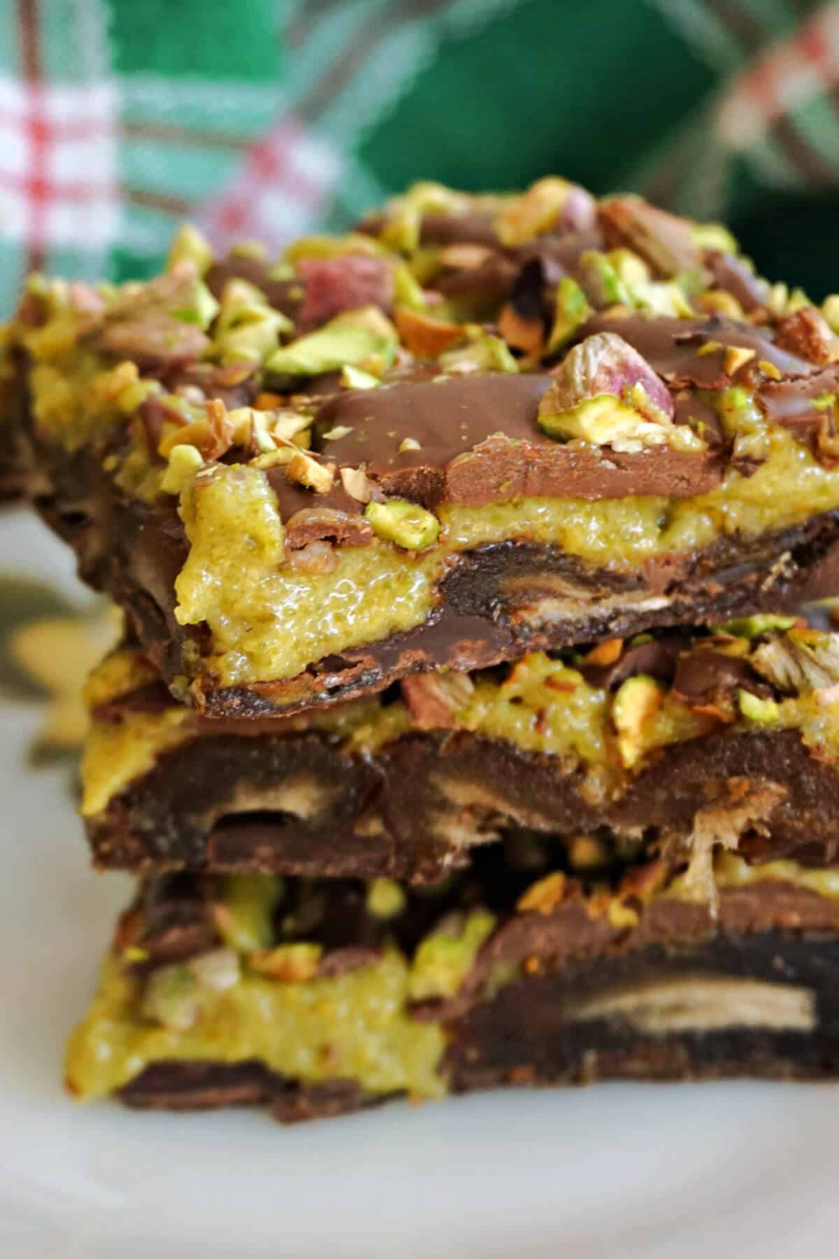A stack of 3 date bark slices with a green-patterened tea towel in the background.