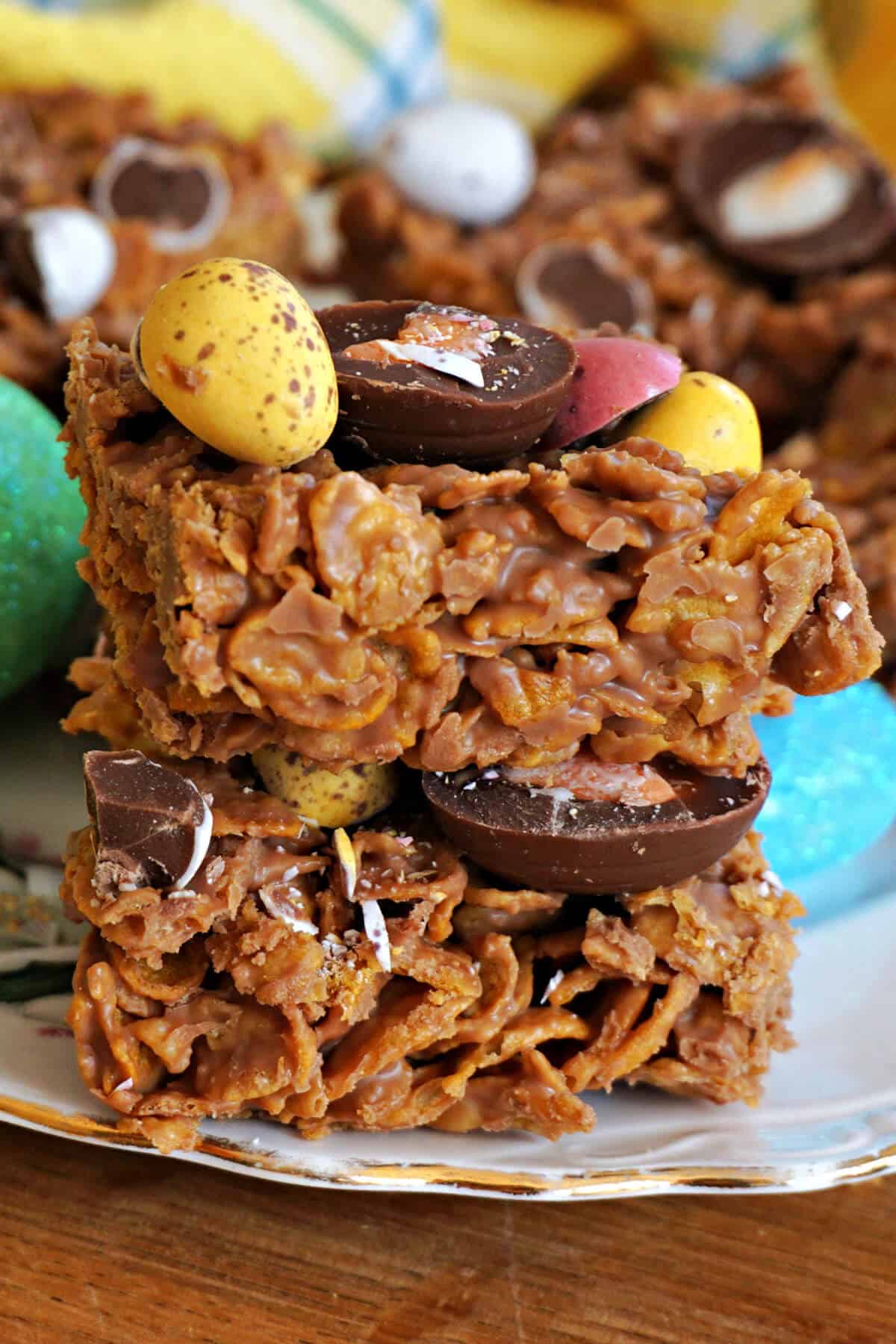 A stack of 2 chocolate cornflake squares topped with mini chocolate eggs.