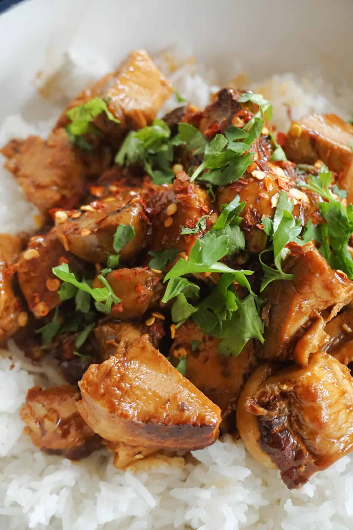 Pork stir fry garnished with chopped parsley over a bed of rice.