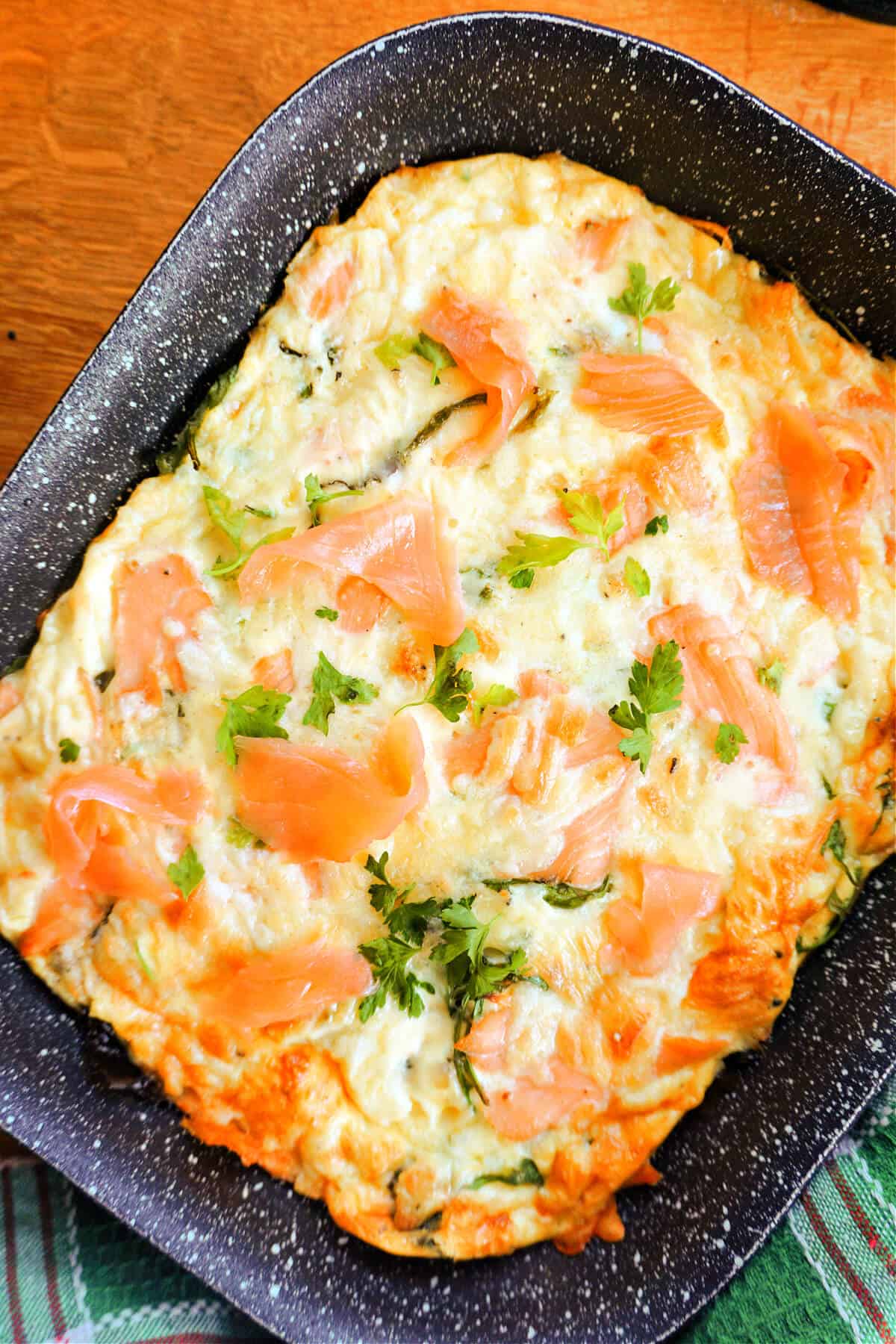 A baking tray with a frittata topped with smoked salmon and chopped parsley.
