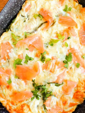 A roasting tray with frittata topped with chopped parsley and smoked salmon.