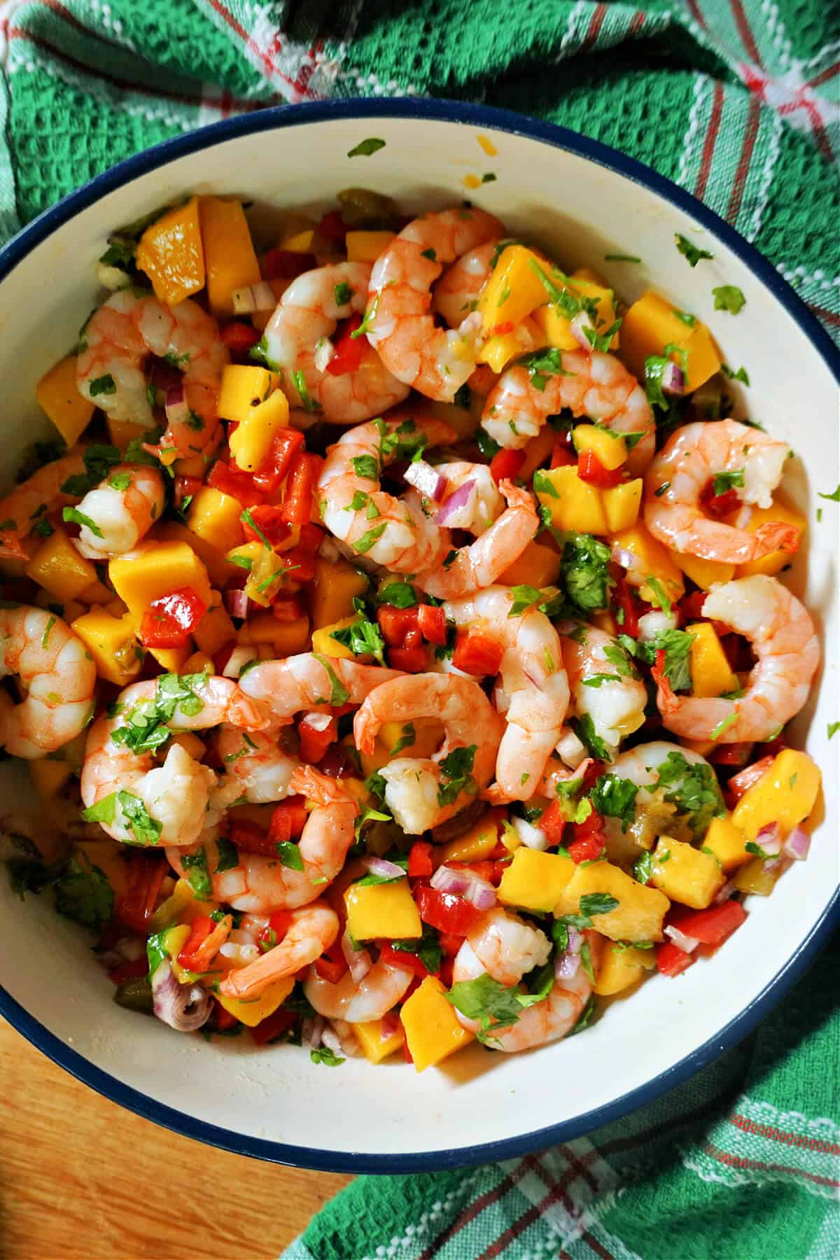 A white bowl with prawn and mango salad.