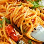 A fork twisting spaghetti in red sauce.