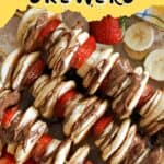 2 pancake skewers with banana and strawberry sliced and drizzled with melted chocolate.