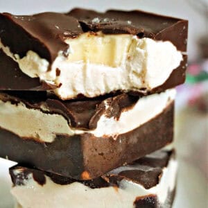 A stack of 3 ice cream bars with the top one hal bitten to reveal a slice of banana inside.