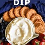 A white bowl with cheesecake dip surrounded by round cookies and berries.