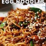 Close-up portion of beef stir fry with noodles garnished with sesame seeds.