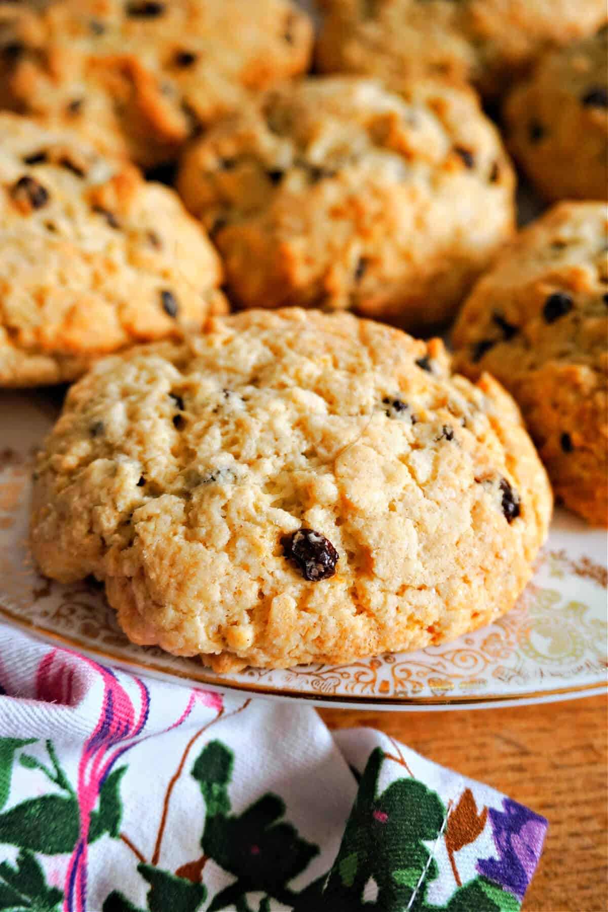 A plate with 4 rock cakes and a flowery tea towel around.