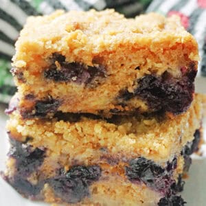 A white plate with a stack of 2 slices of blueberry and banana cake.