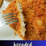 Half a pork escalope on a fork resting on a whole escalope.