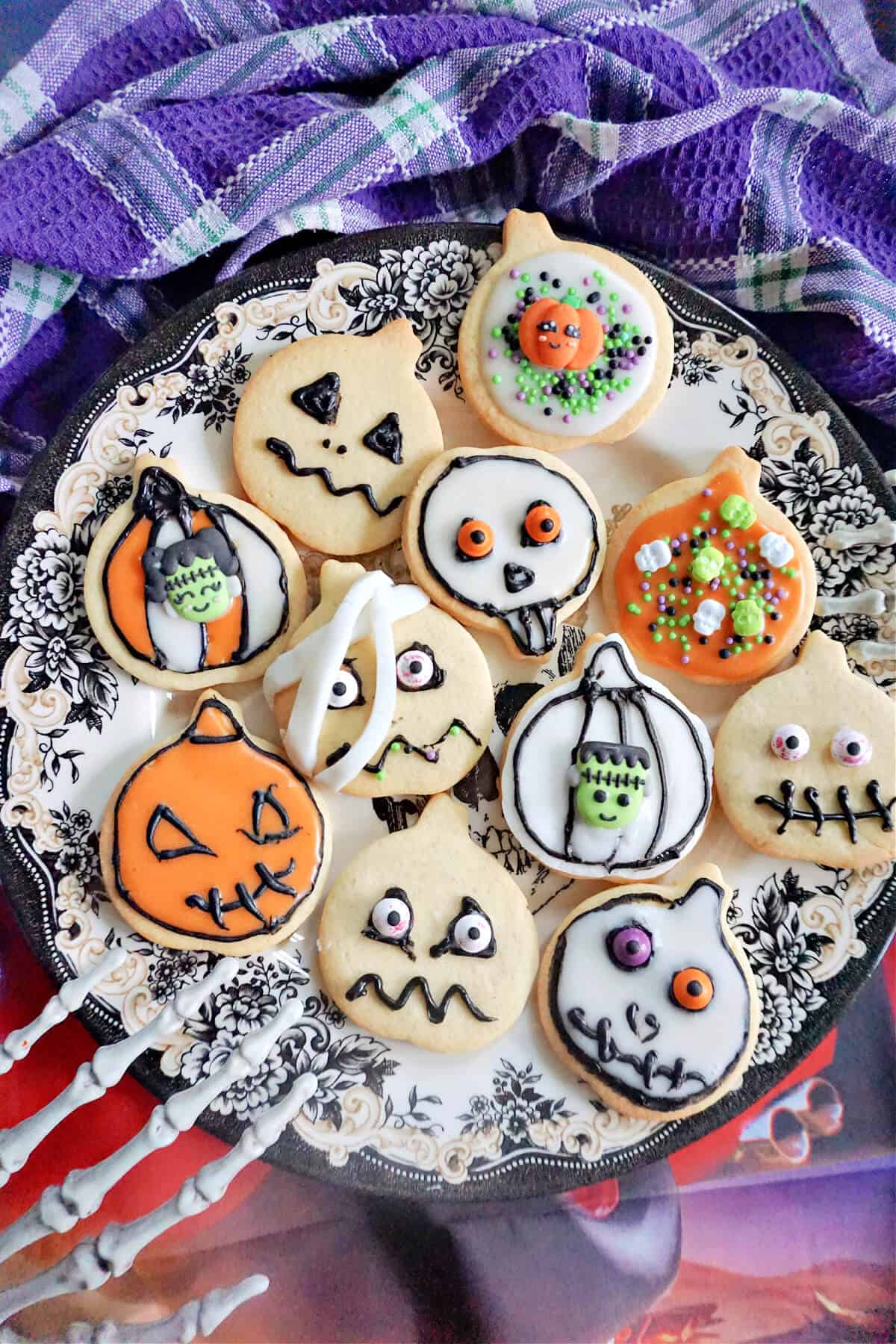 A plate with Halloween sugar cookies and a skeleton hand grabbing the side of the plate.